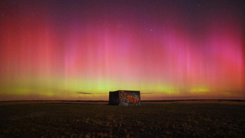 Küçük bir binanın üzerinde sarı pembe ve kırmızı aurora