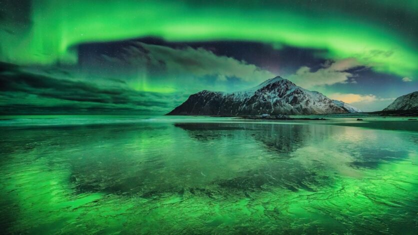 Bir dağı ve gölü çevreleyen yeşil aurora