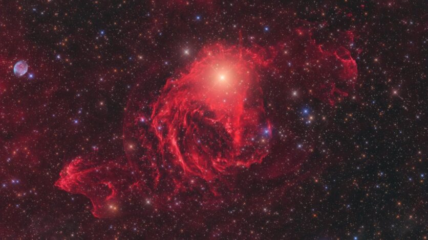 Kırmızı galaktik nebula yıldızlardan oluşan bir arka plan üzerinde parlıyor
